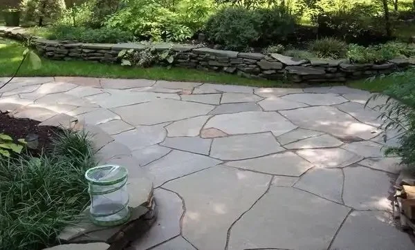 Flagstone patio with curved stone edges surrounded by mature garden landscaping