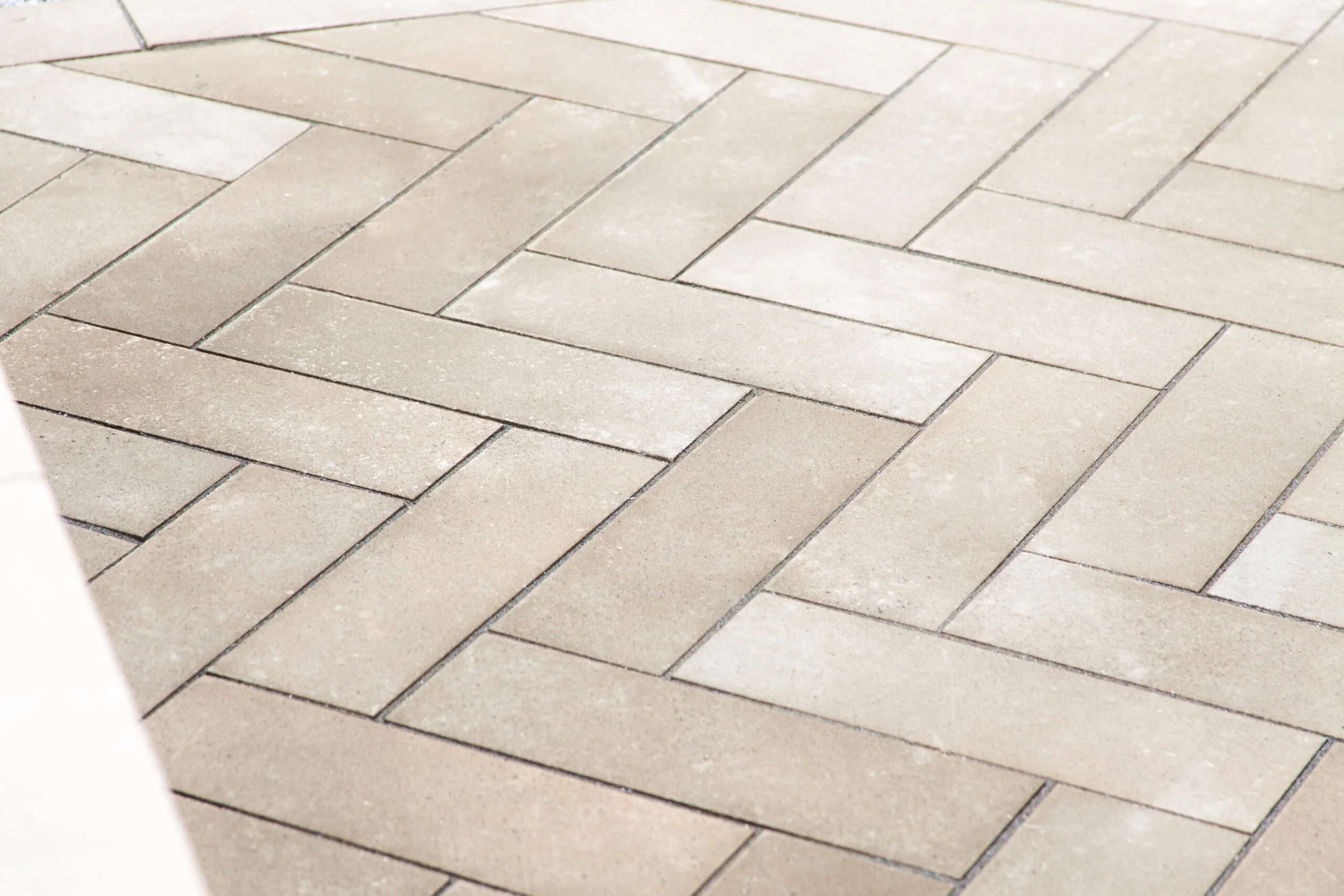 Herringbone-pattern natural stone patio paving in a modern outdoor space