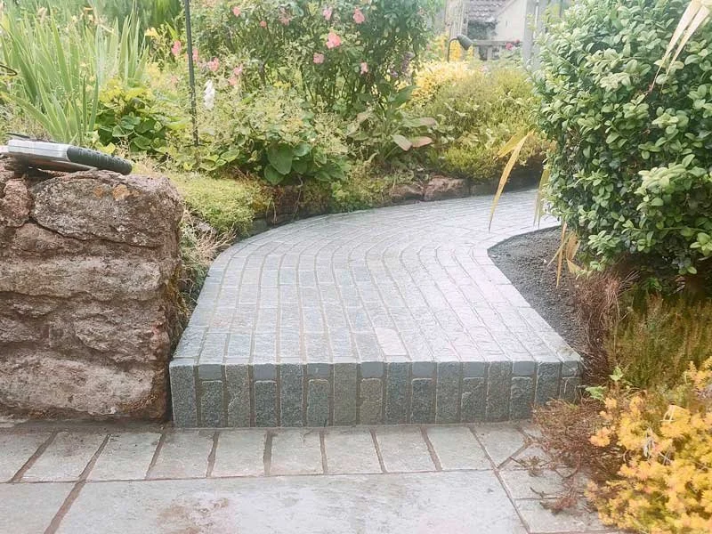 Curved stone bridge walkway integrated into a garden path design