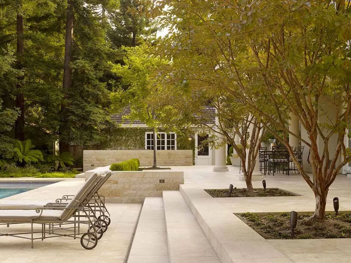 Modern courtyard with stone seating steps and mature trees providing shade