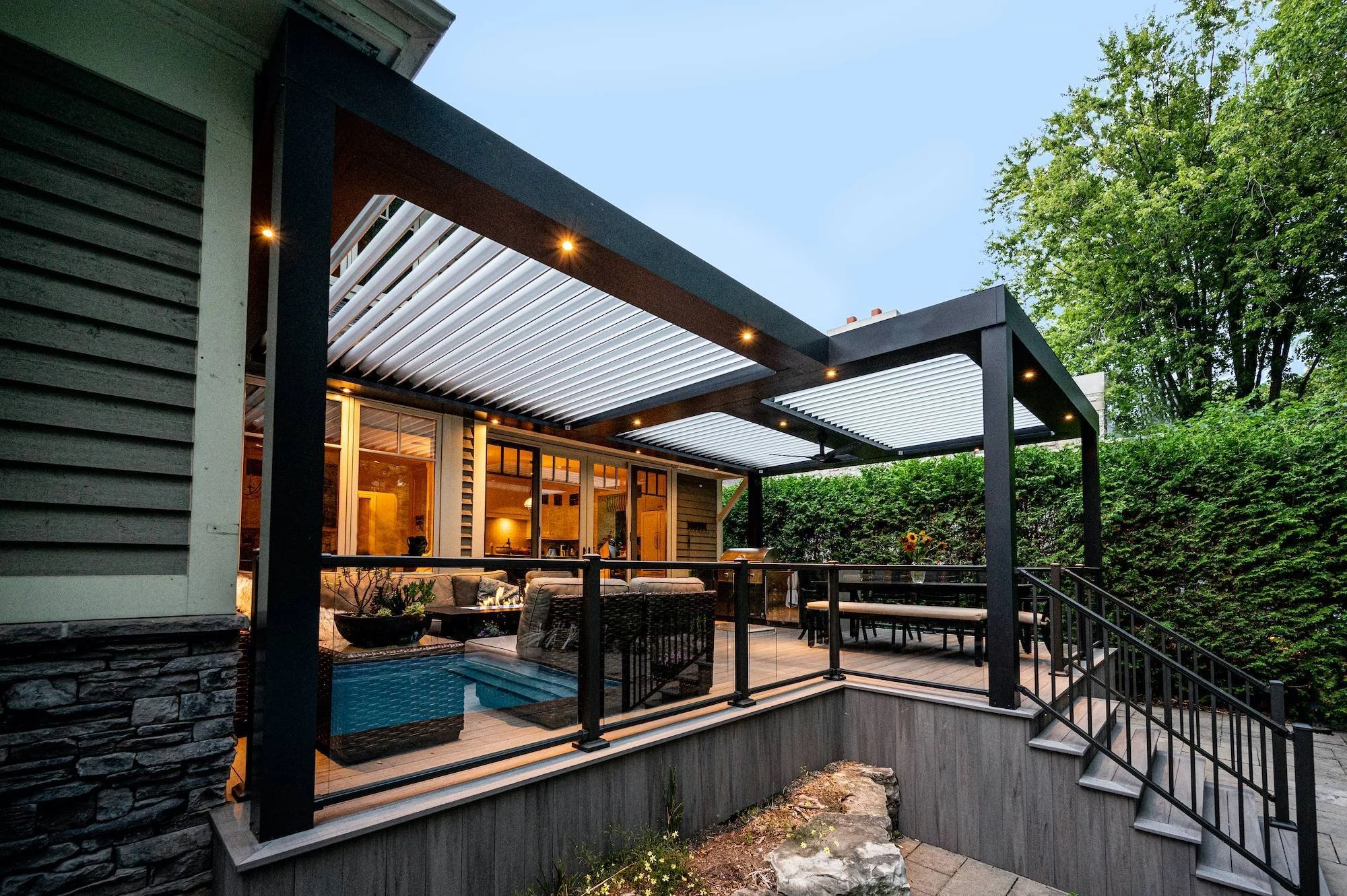 Contemporary covered deck with black pergola frame, outdoor sectional seating, and ambient lighting for evening entertaining.