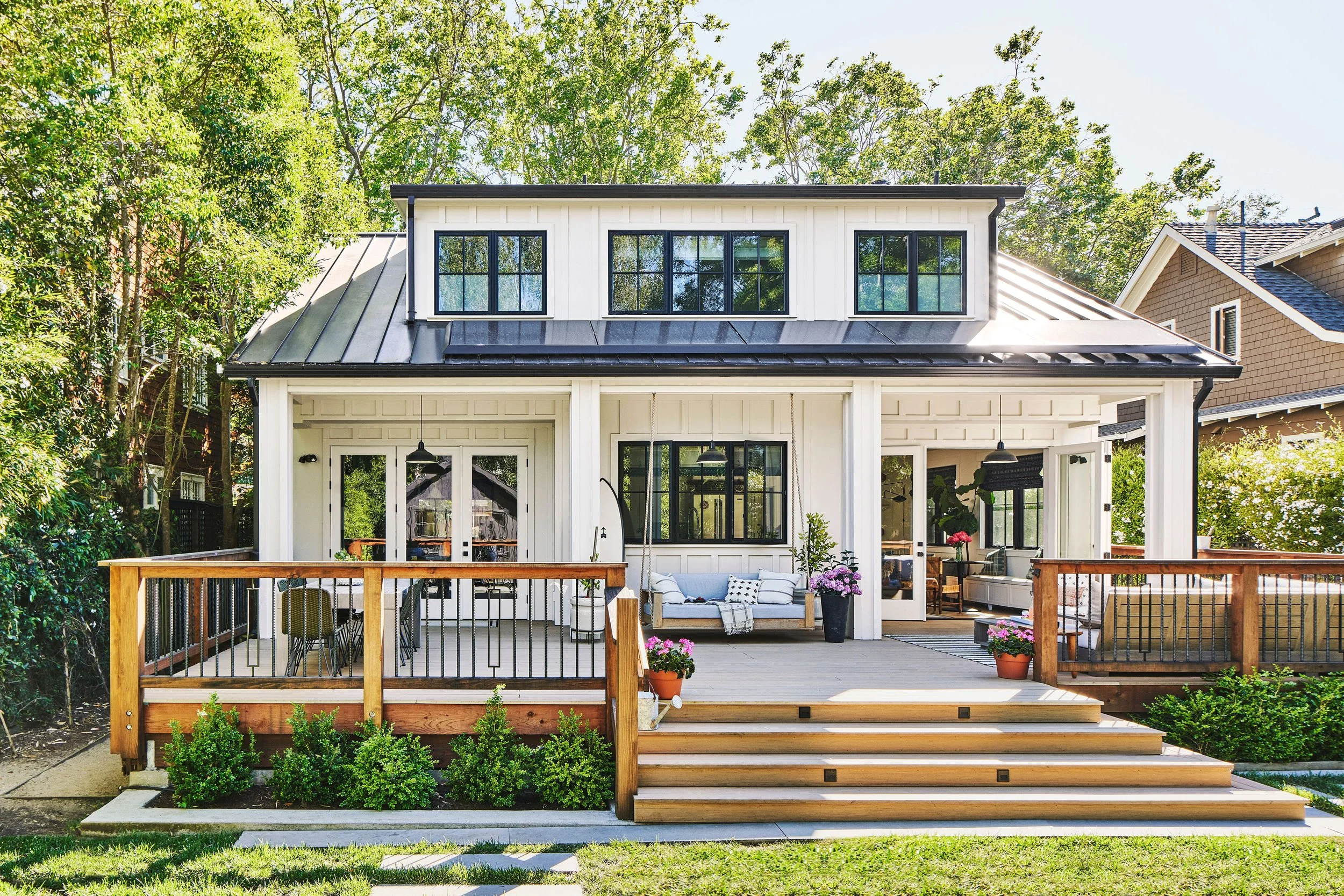 Front porch style raised deck with black railings, wood steps, and modern farmhouse exterior design.