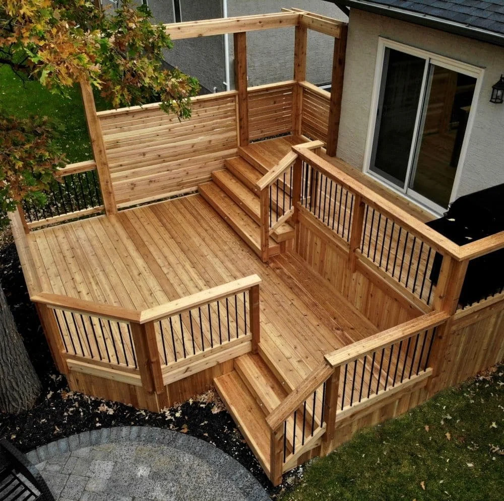 Multi-level wood backyard deck with stairs, railings, privacy screen, and sliding patio door entrance.