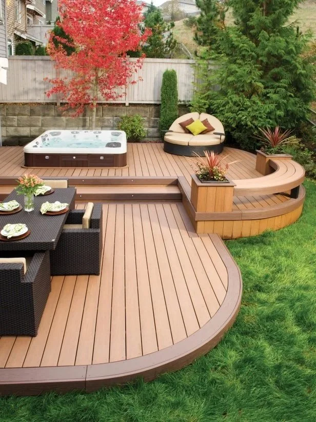 Curved composite deck with built-in hot tub, rounded bench seating, and modern outdoor lounge area.