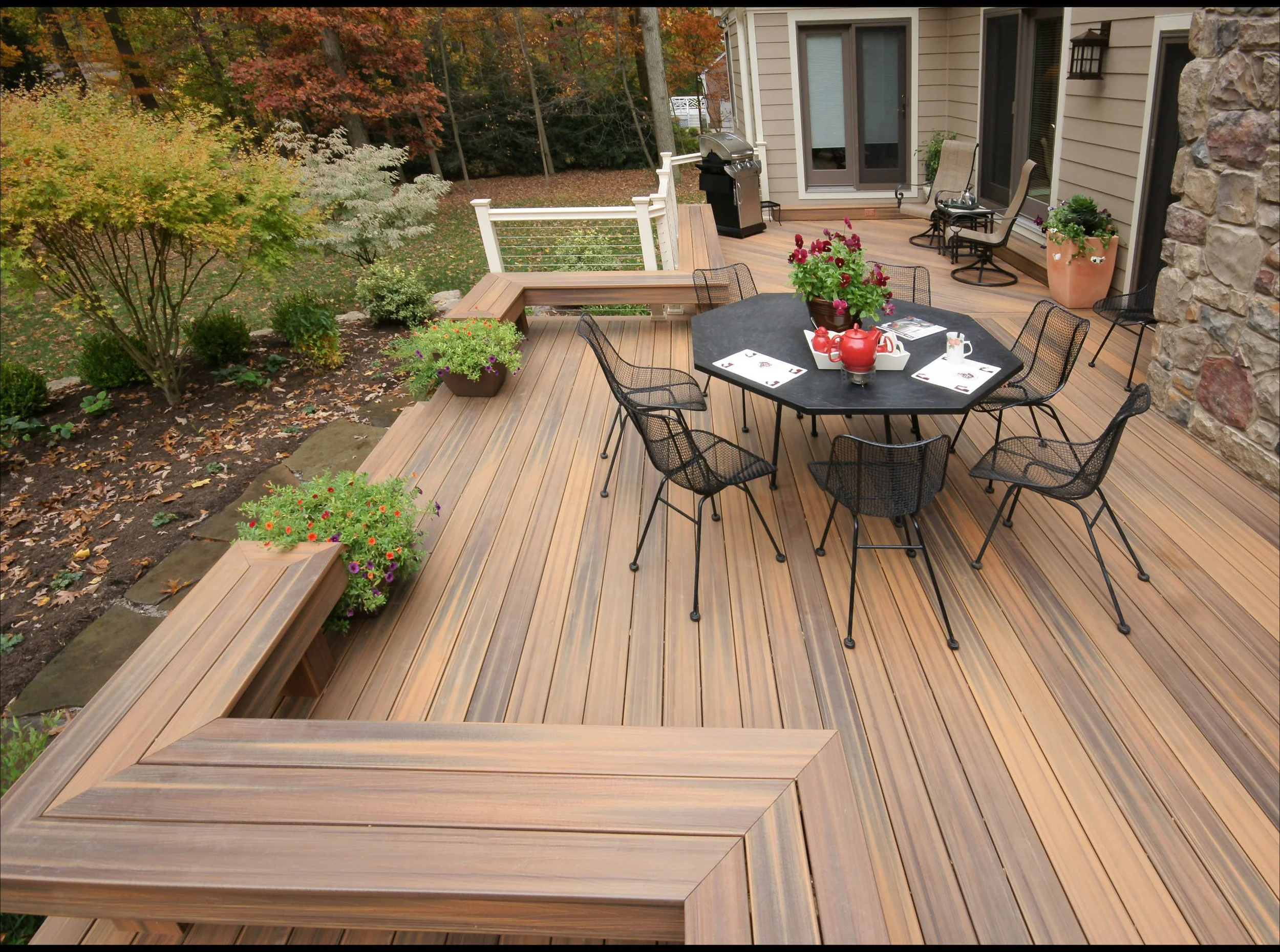 Spacious wood deck with built-in bench seating, outdoor dining table, and backyard garden views.
