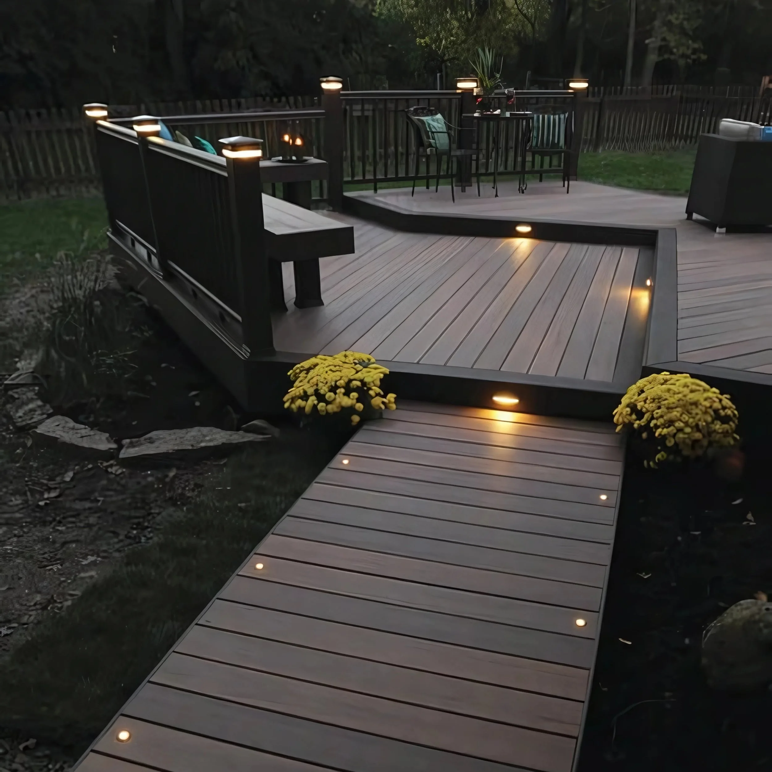 Modern backyard deck with built-in step lighting and illuminated walkway leading to raised platform.