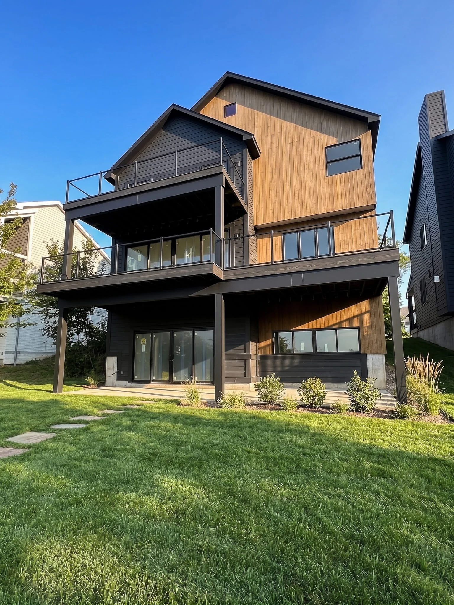 James Hardie fiber cement siding with wood accent panels and black metal railing on modern multi-story lakefront home