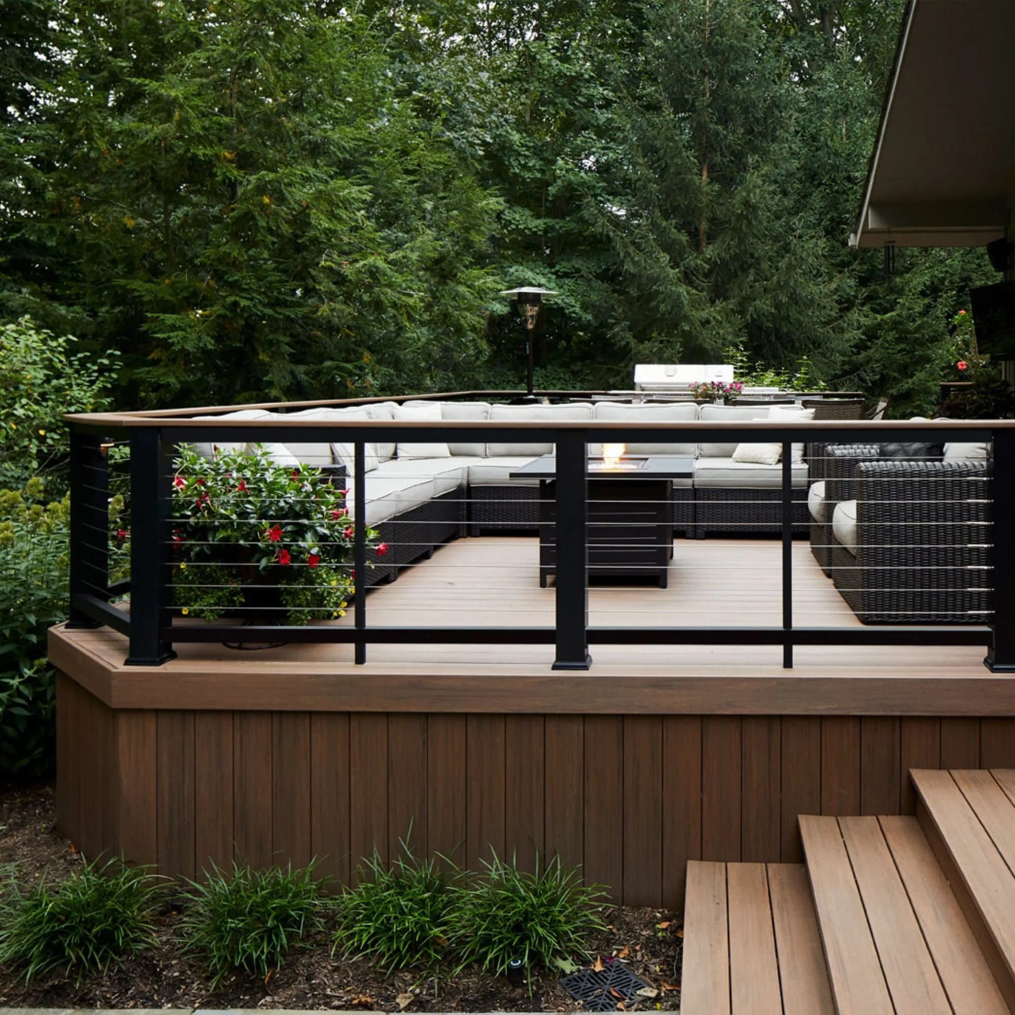 TimberTech composite deck with warm brown boards and patio furniture surrounded by trees