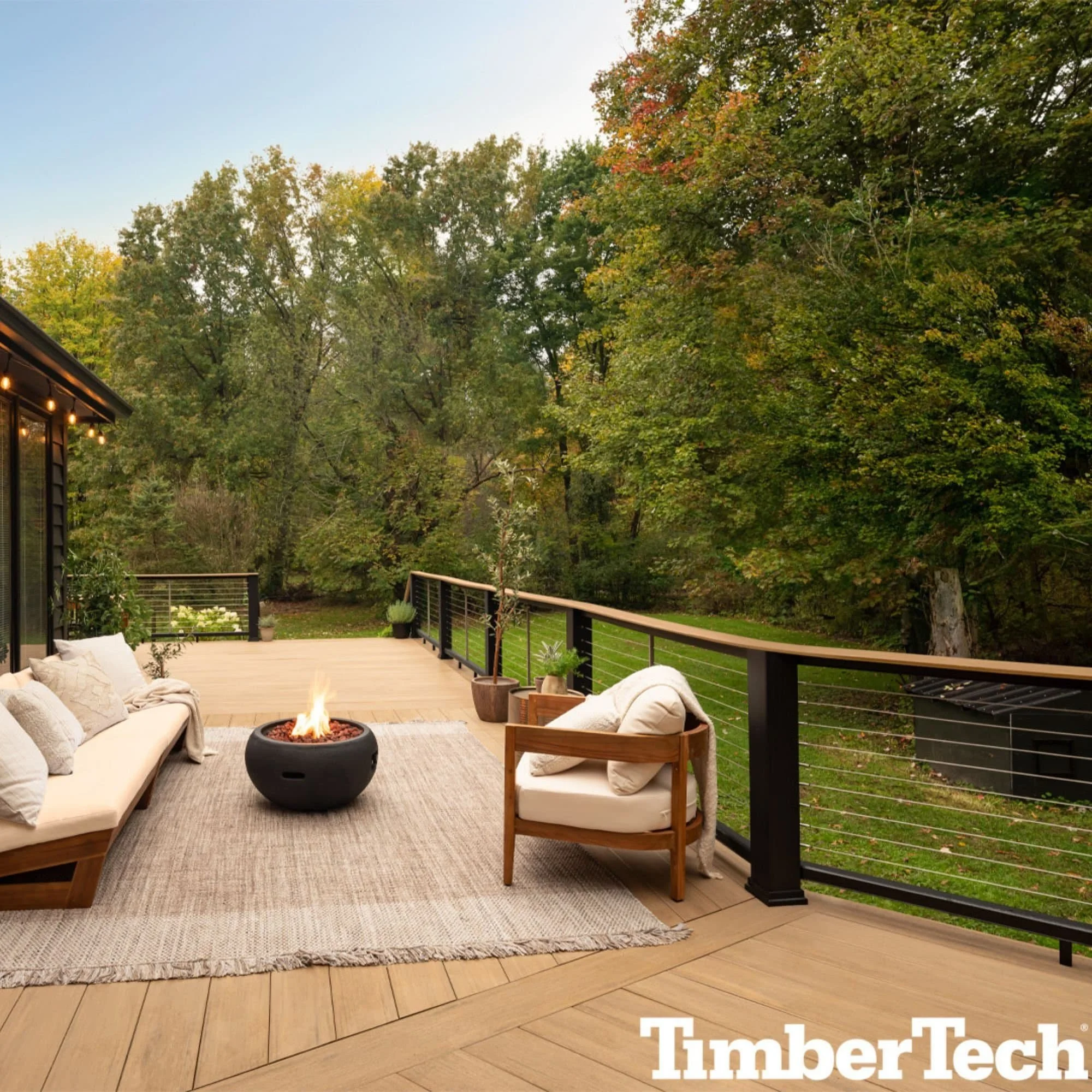 TimberTech composite deck with dark brown boards and black metal railing overlooking wooded backyard