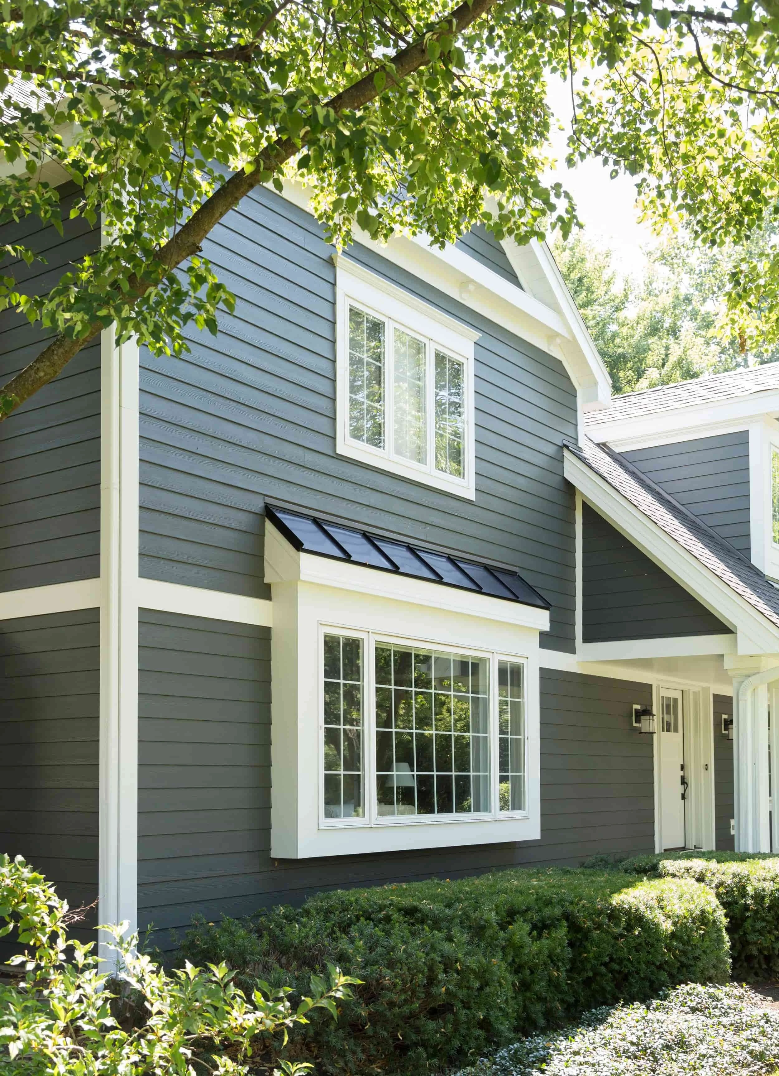 Dark gray James Hardie fiber cement siding with white trim on two-story home surrounded by trees