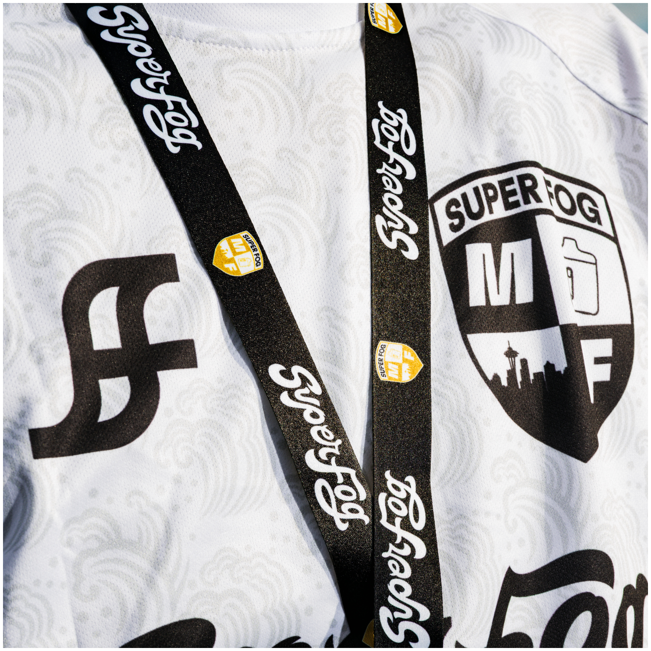 Close-up of a hockey jersey with black laces and patches that say 'Super Fog' and feature a cityscape and the Space Needle