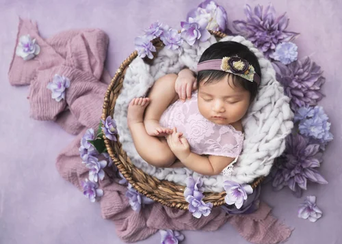 Newborn girl with a headband sleeping in a basket with purple flowers on a lilac backdrop, Mountain View newborn photographer