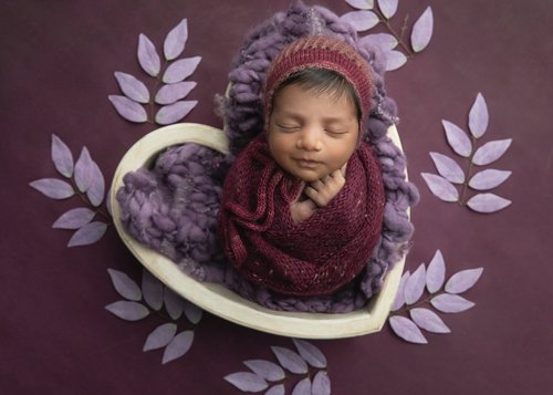 Newborn in a burgundy knit bonnet in a white heart bowl with lilac leaves on a plum backdrop, Mountain View newborn photography studio