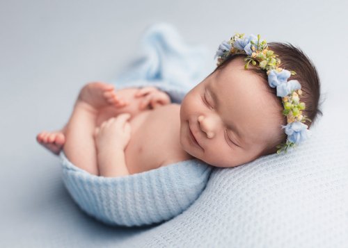 Newborn girl with a blue flower crown in a blue knit wrap on a pale blue backdrop, Mountain View newborn photographer