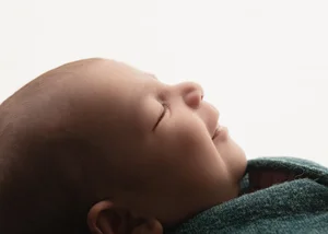 Close-up profile of a sleeping newborn against a white backdrop, Bay Area newborn photography session