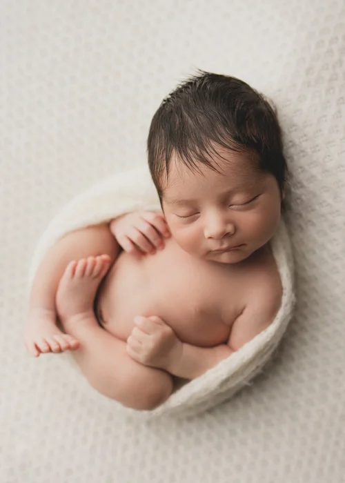 Newborn curled up and sleeping on a cream blanket, Mountain View newborn photography studio