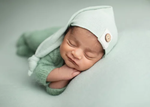 Newborn in a mint sleepy cap and green knit outfit sleeping on a mint blanket, Bay Area newborn photography session