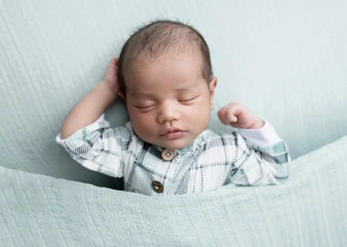 Newborn boy in a plaid shirt tucked into a mint blanket with hands by his head, Mountain View newborn photographer