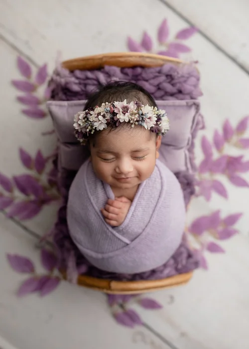 Newborn girl swaddled in lavender with a flower crown on a purple leaf backdrop, Mountain View newborn photography studio