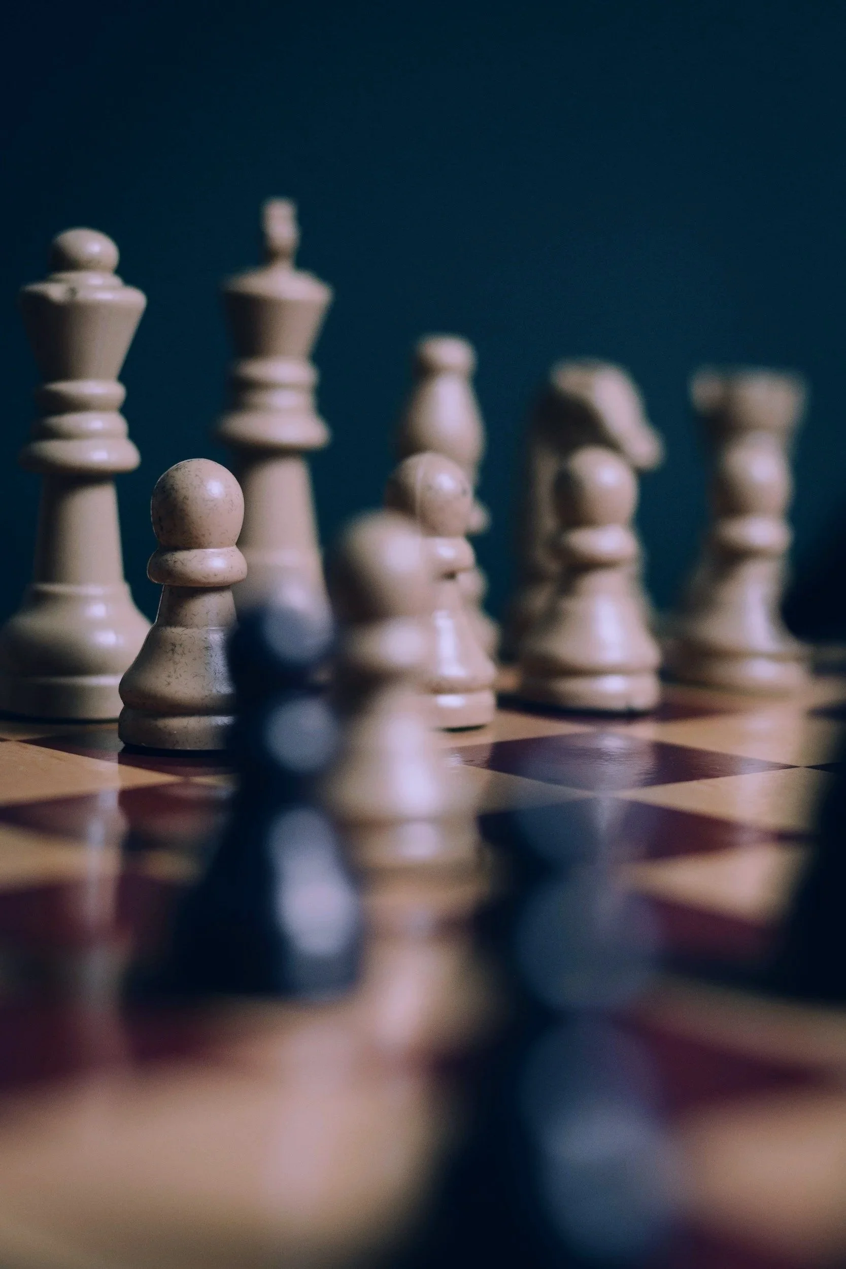 Close-up of a chessboard with chess pieces, focusing on the pawns, with a dark background.