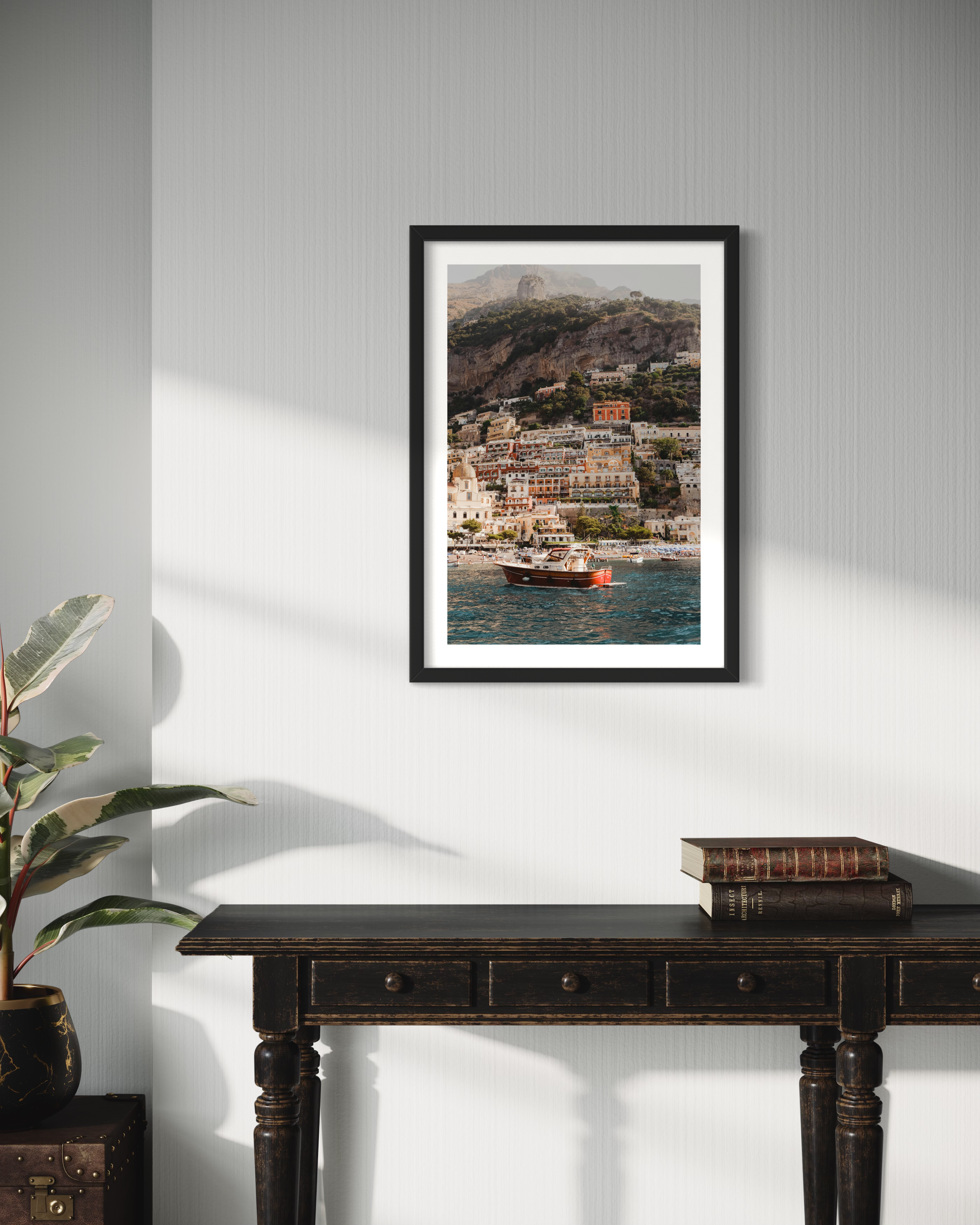 In this picturesque photo of Positano, a charming boat gracefully rests on the vivid waters, framed by a backdrop of colorful buildings that cling to the steep mountainside