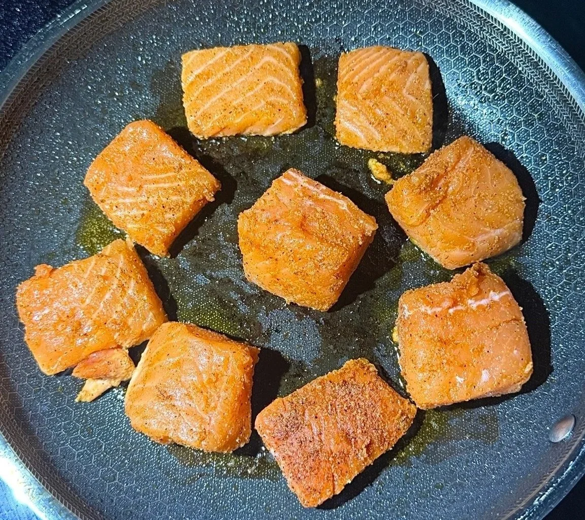 Salmon cubes searing in a skillet for a salmon rice bowl recipe