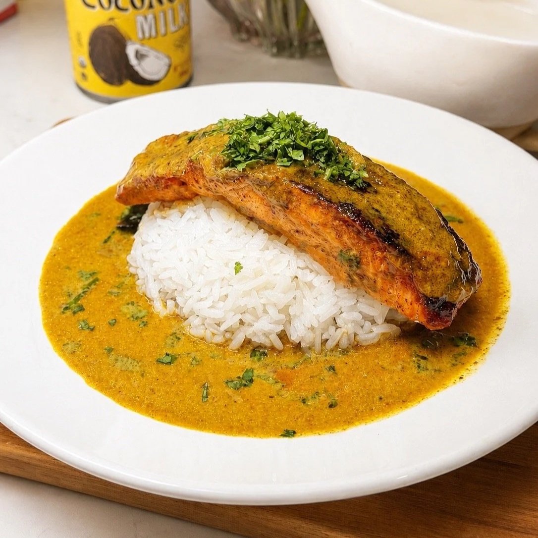 Plated coconut curry salmon with rice garnished with cilantro and lime