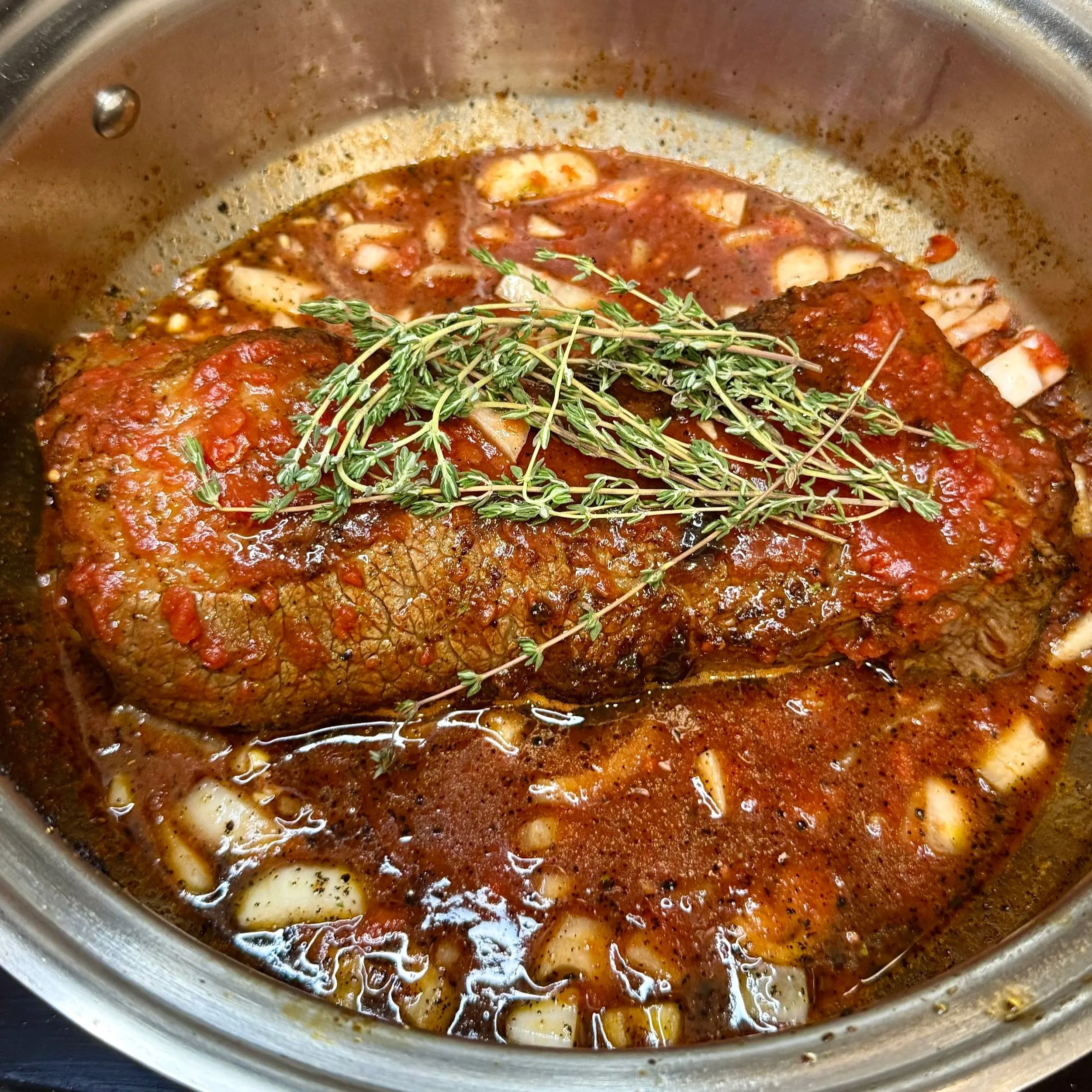 Beef brisket seared in a pan until golden brown, ready for slow cooking in the collagen‑infused sauce