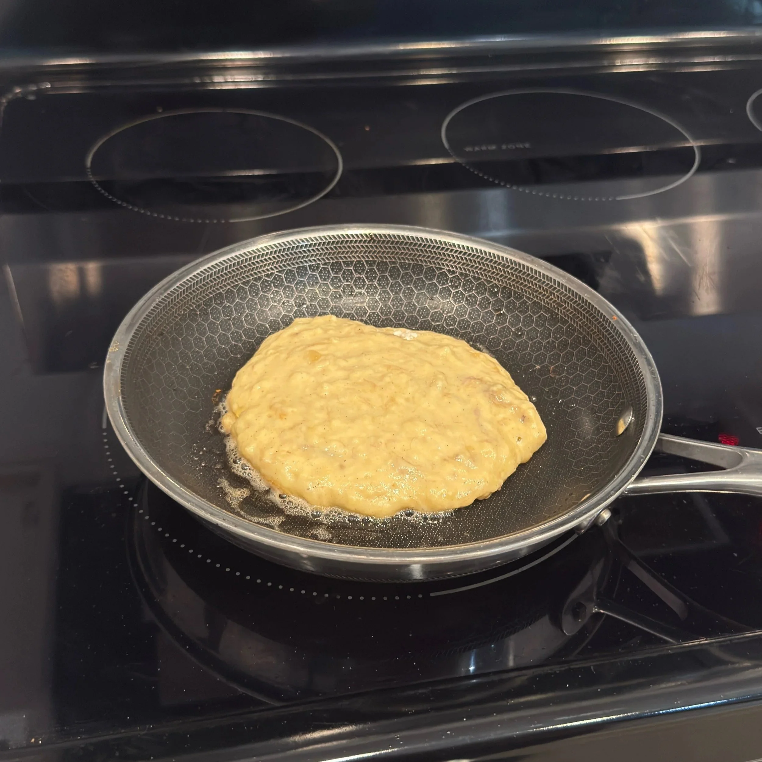 ¼‑cup scoop of banana pancake batter cooking on a hot skillet.
