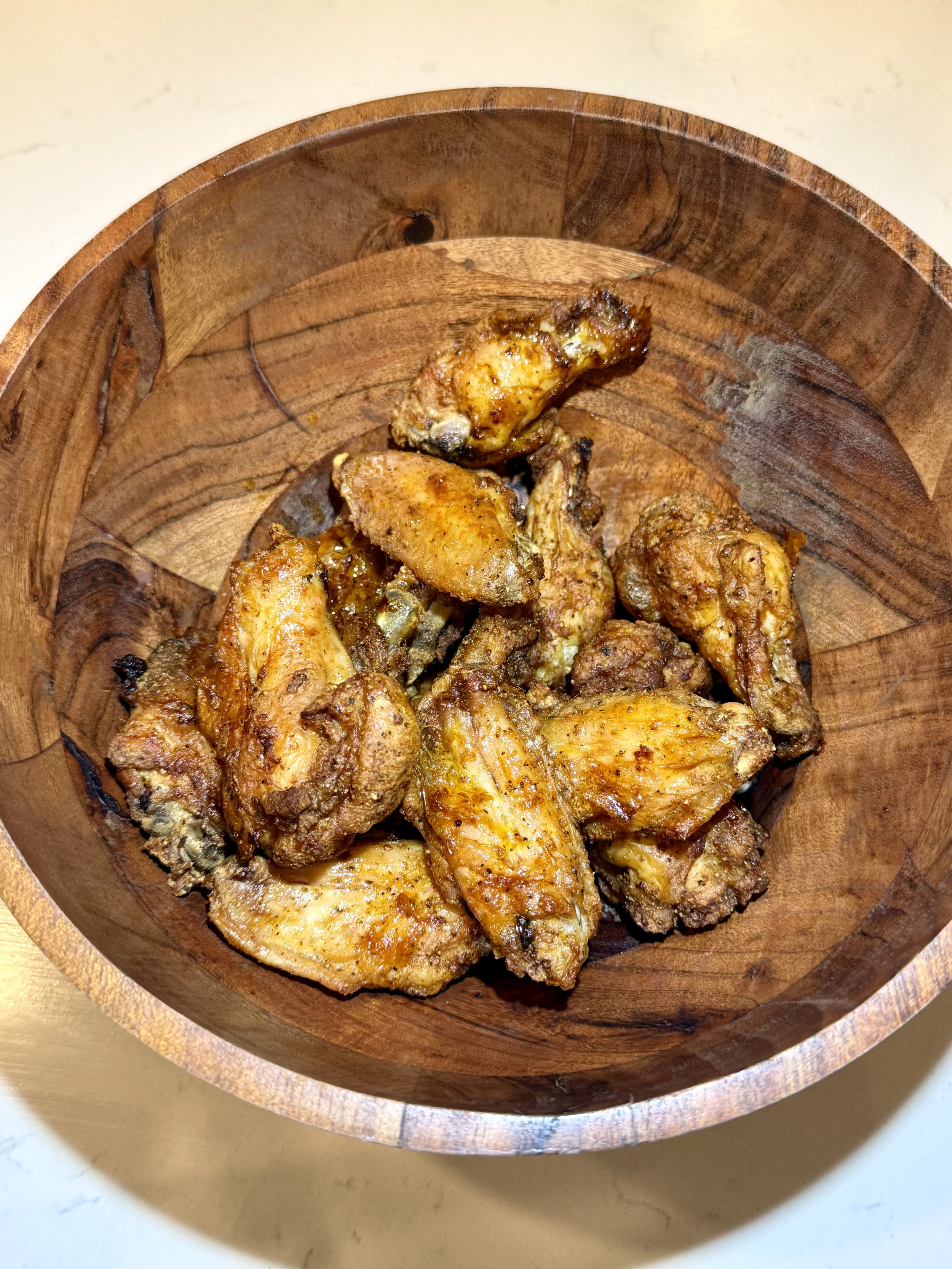 Golden crispy wings fresh out of the air fryer in a wooden bowl