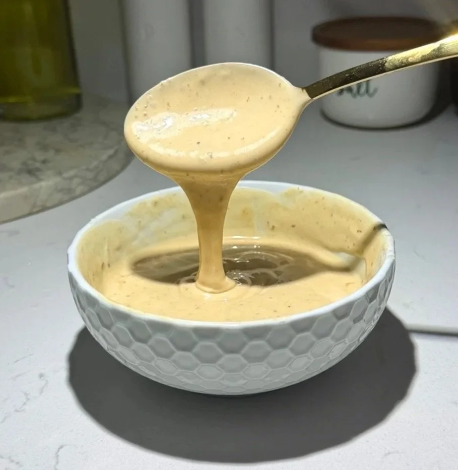 Spicy mayo sauce dripping from a spoon showing thick drizzle consistency