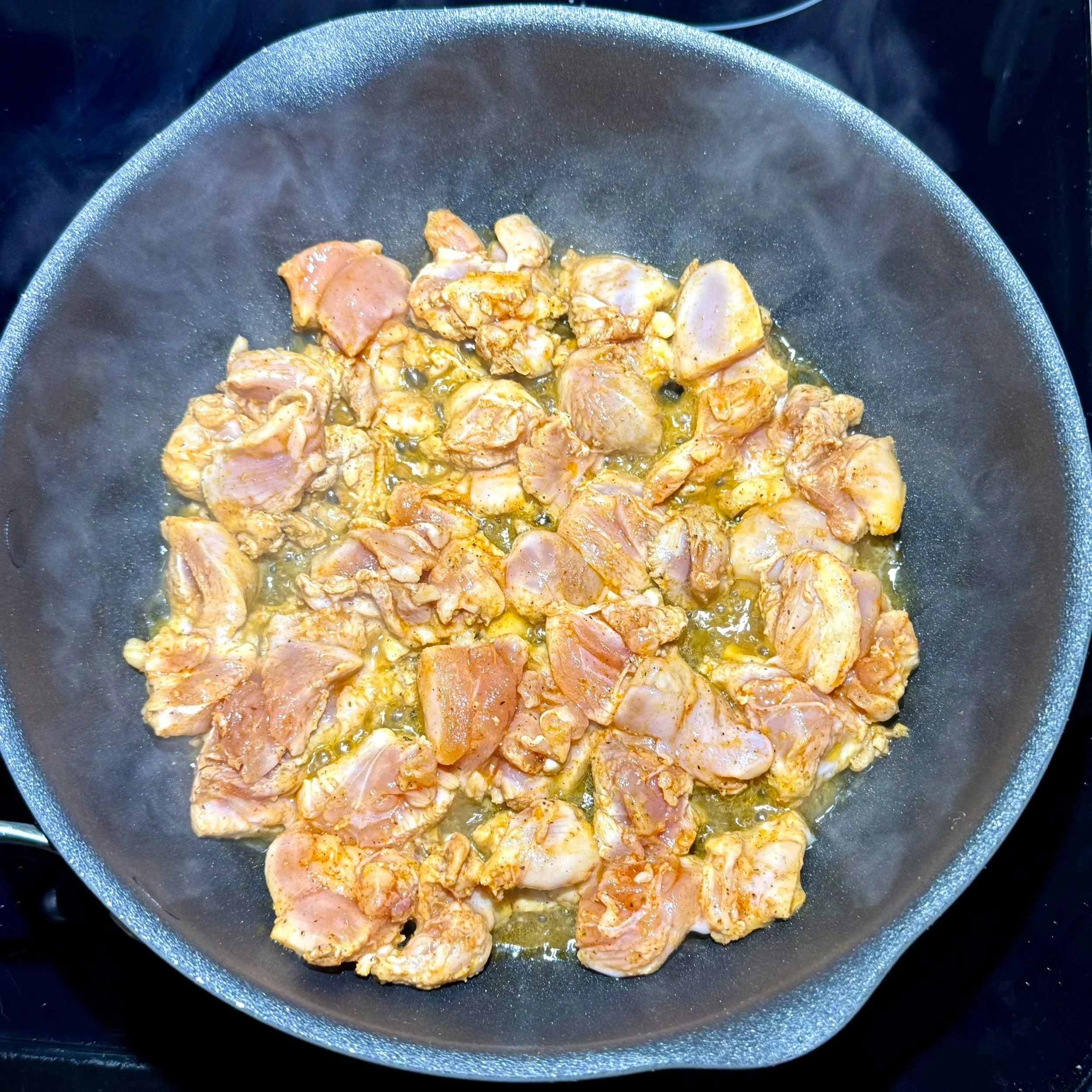chicken pieces searing in a skillet until lightly browned