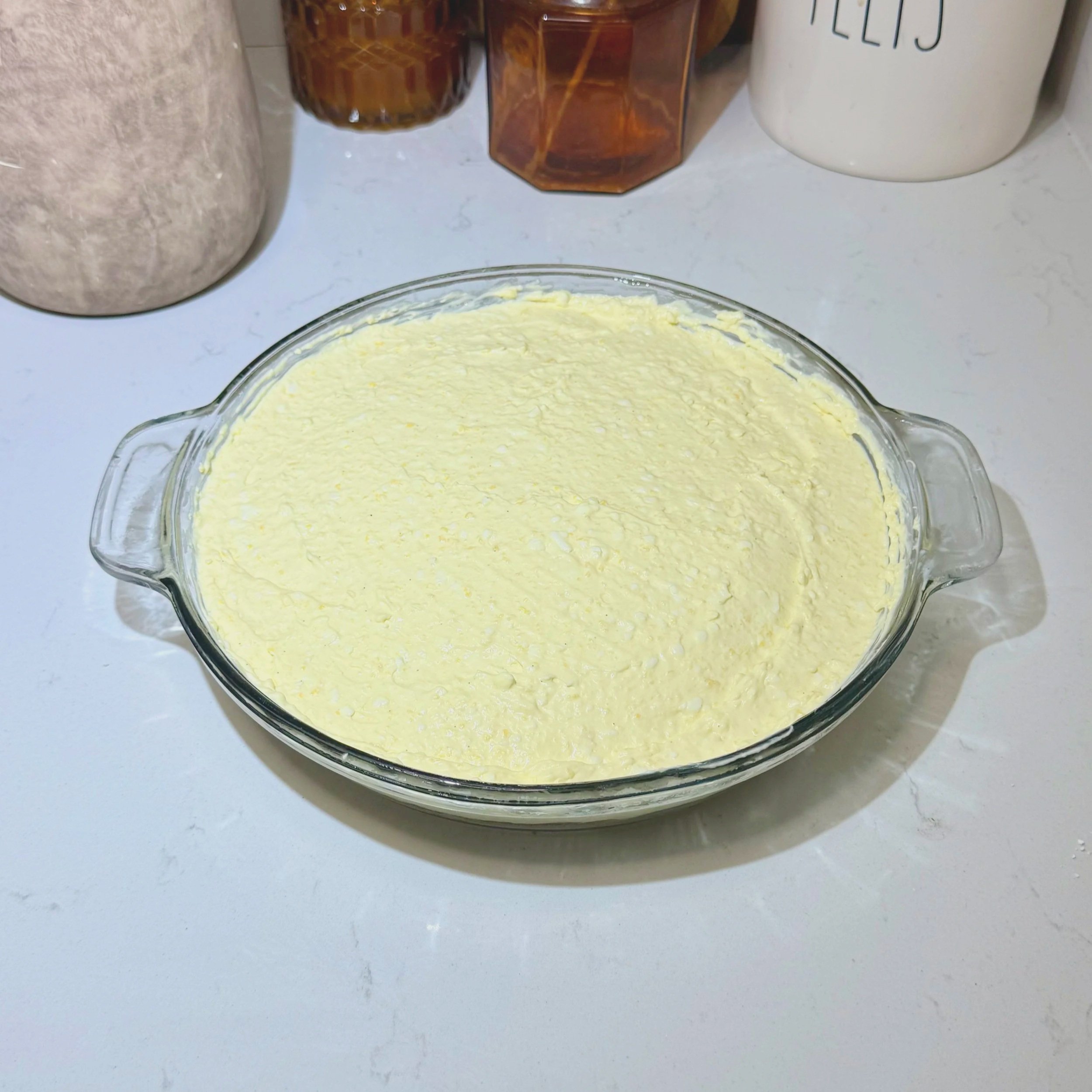 Smooth cheesecake filling spread evenly inside the pie dish