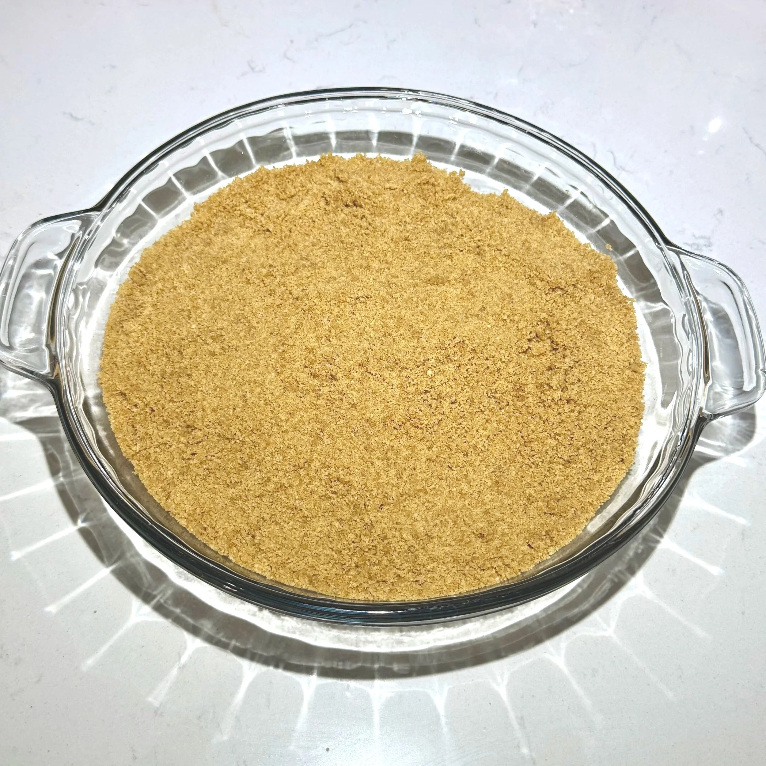 Graham cracker crust pressed firmly into a clear round pie dish