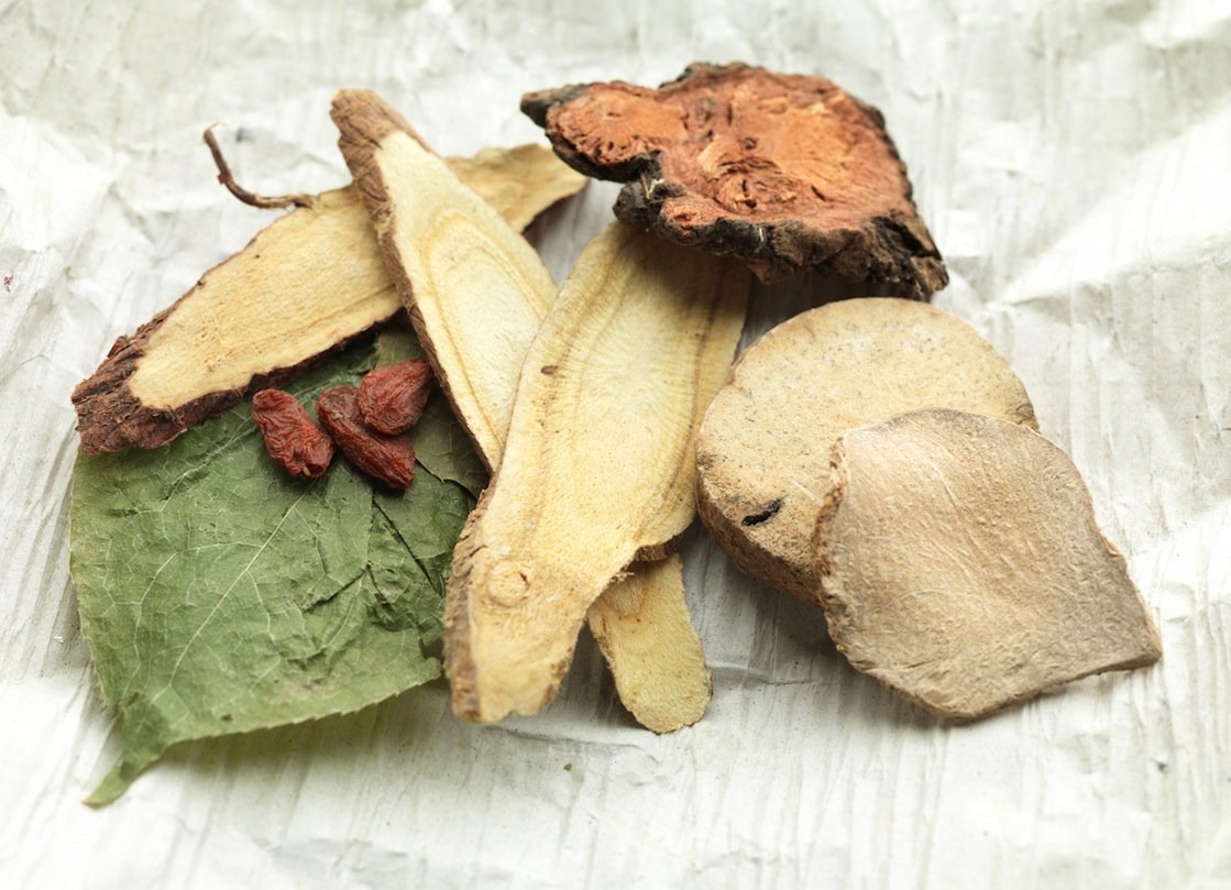 Dried herbs and natural ingredients arranged on a soft textured surface.