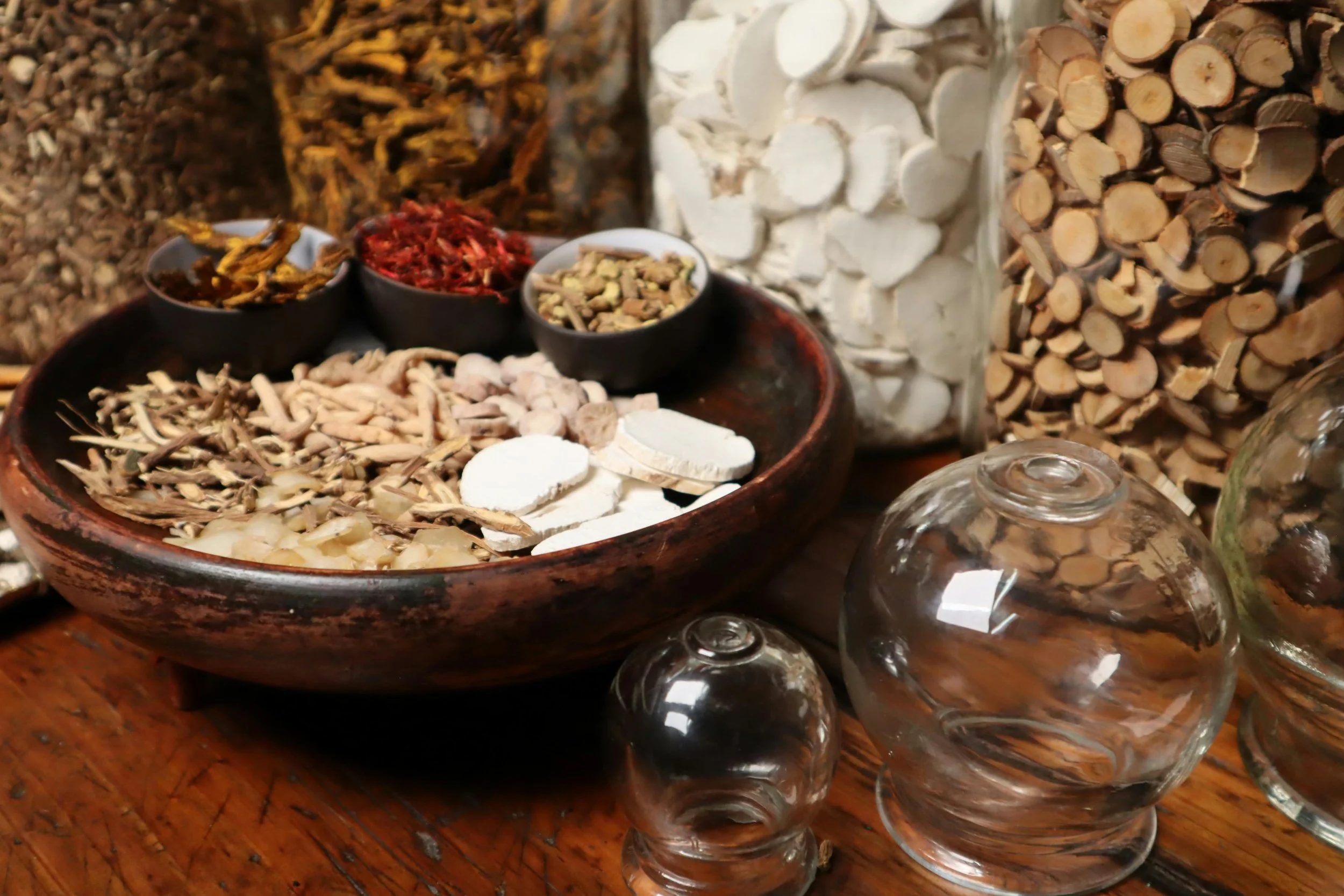Assorted dried herbs and natural ingredients displayed in bowls and wooden containers.