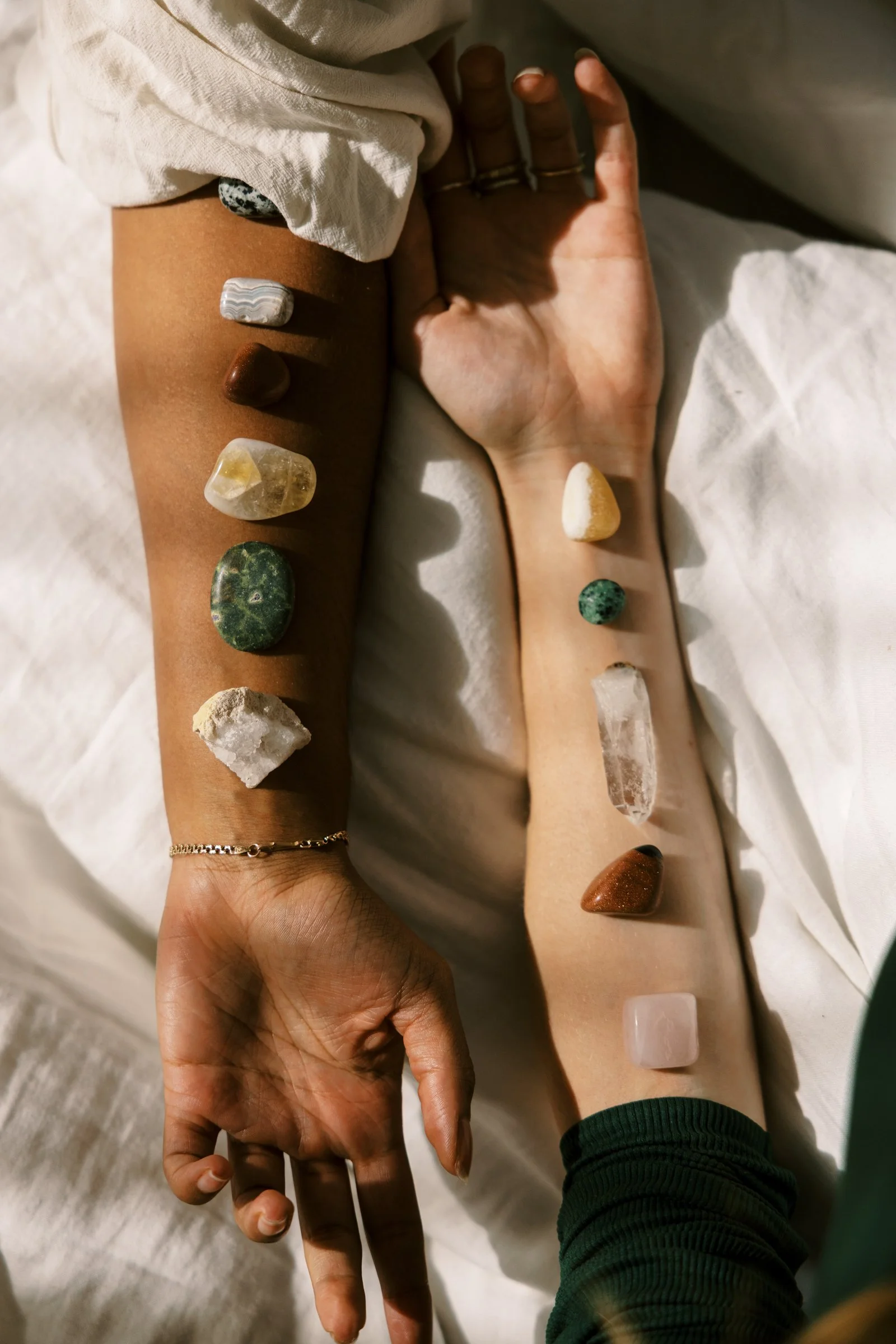 Crystals and stones arranged along a person's arm during a calming wellness session.