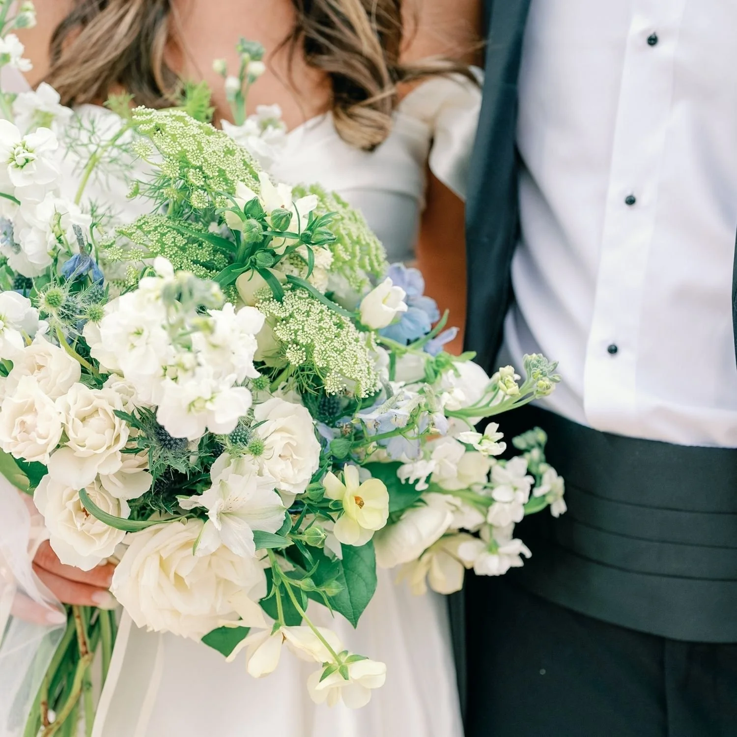 bride and groom with bride holding a bouquet with white and blue flowers
