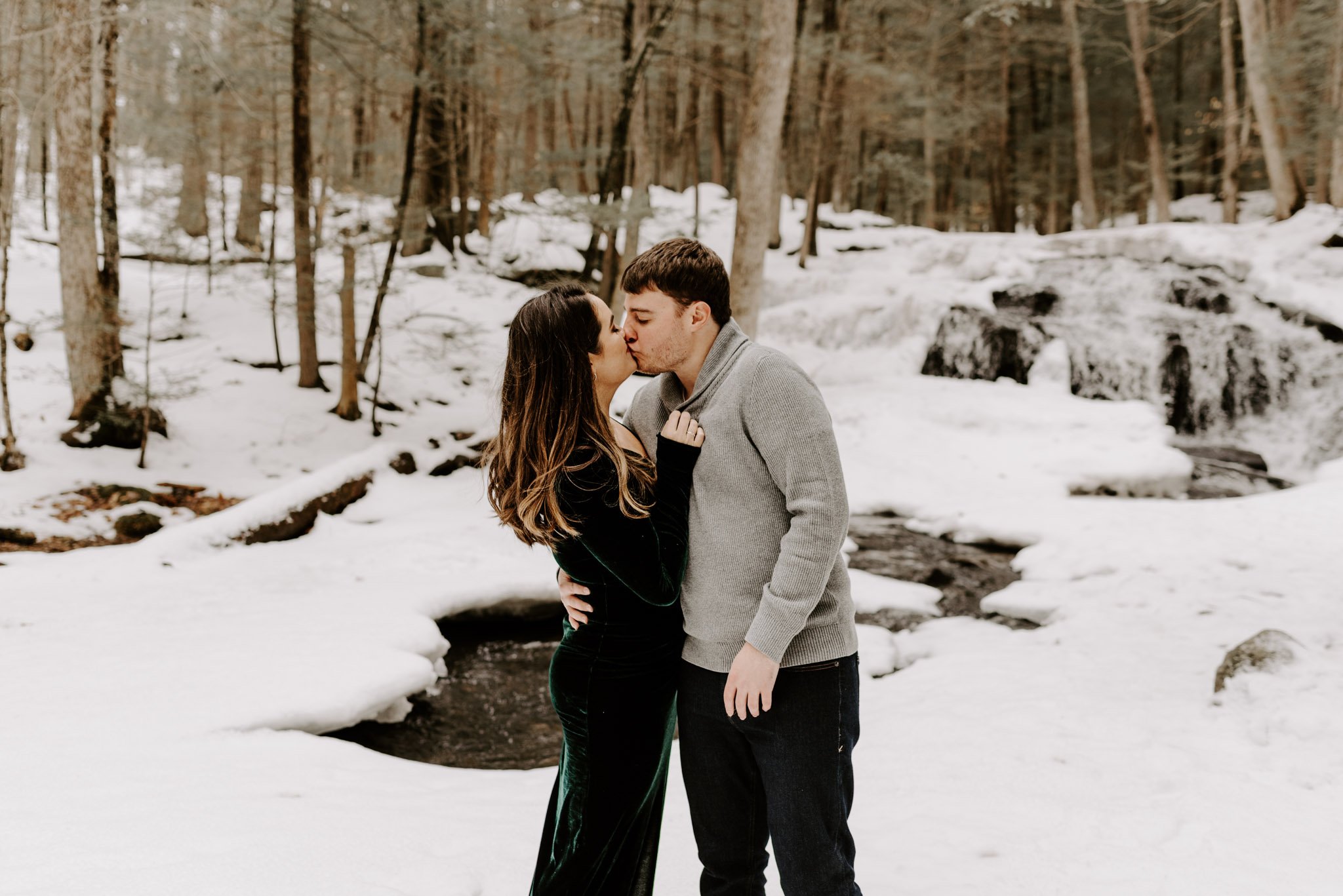 Couple celebrating their winter engagement nearby a waterfall