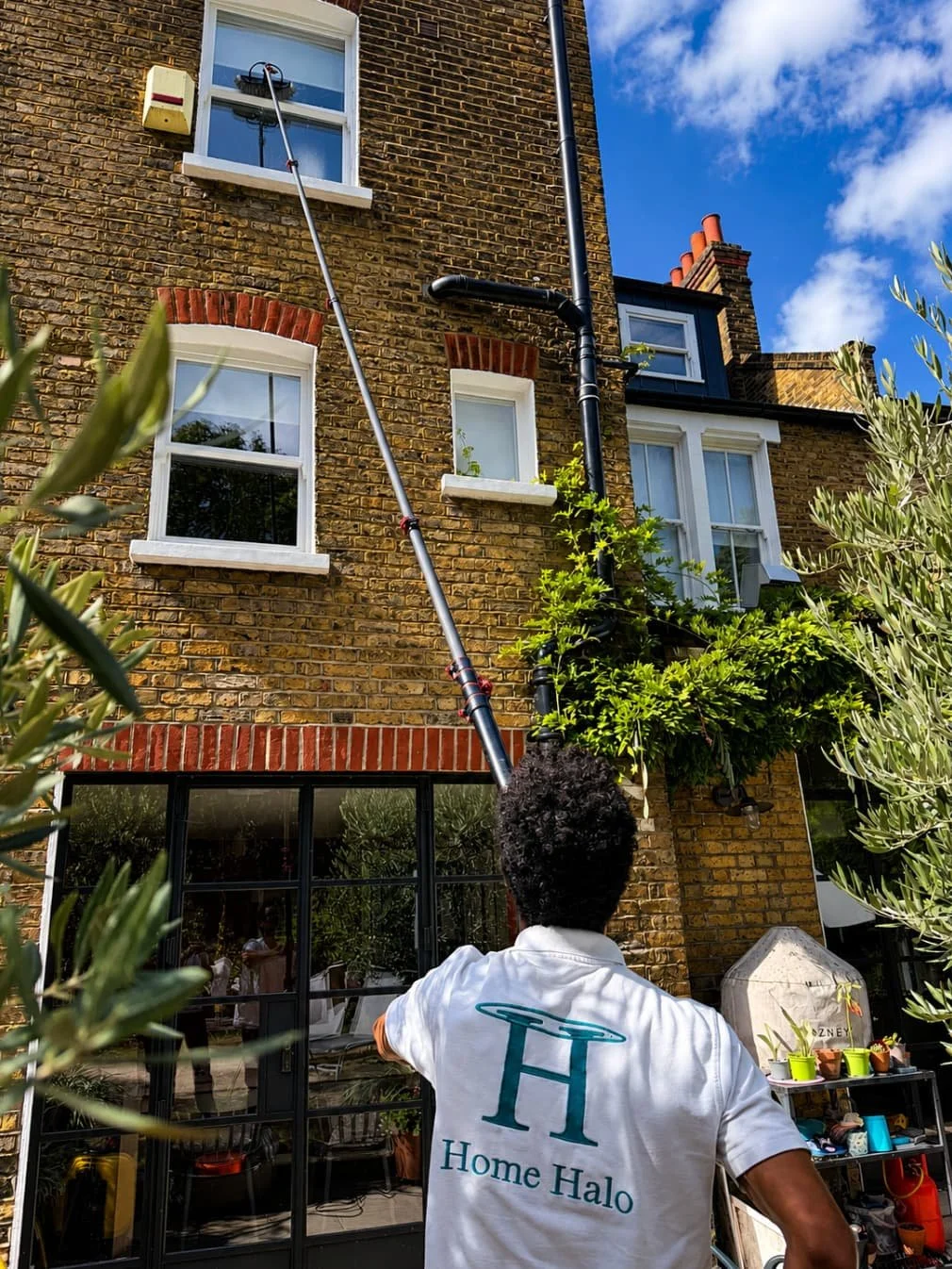 Home maintenance in South London: cleaning the upper windows of a Clapham Victorian terrace with a water-fed pole