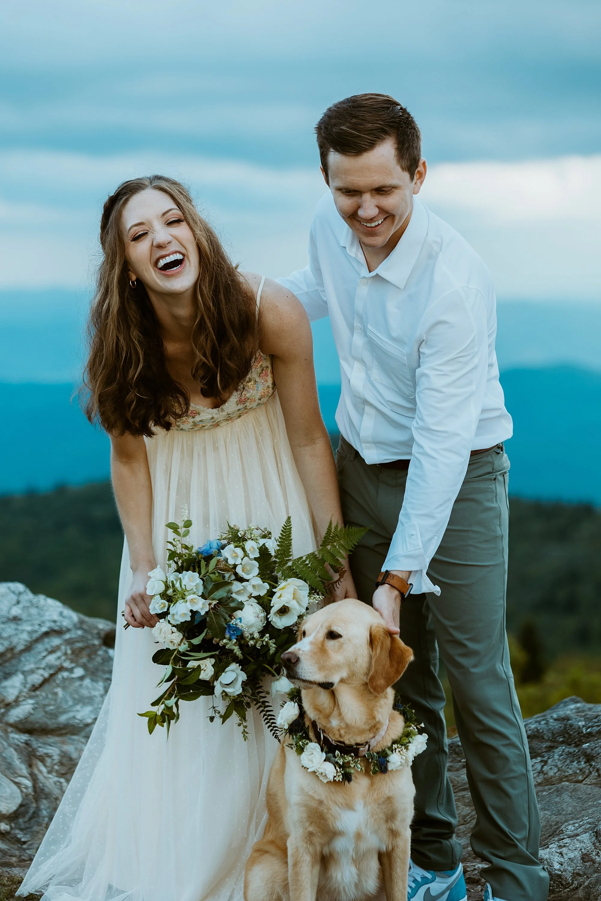 Couple laughs with their dog after they are legally married on top of a mountain during their North Carolina elopement.
