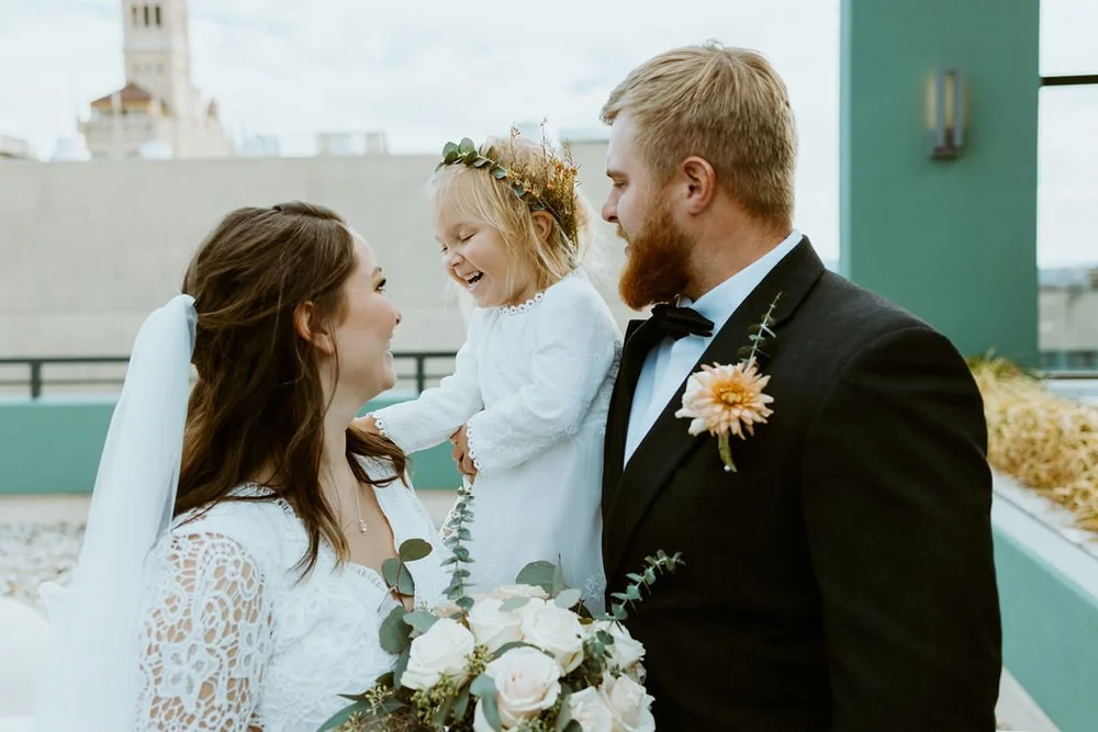 Couple stands with their daughter and laughs together after they elope in North Carolina.