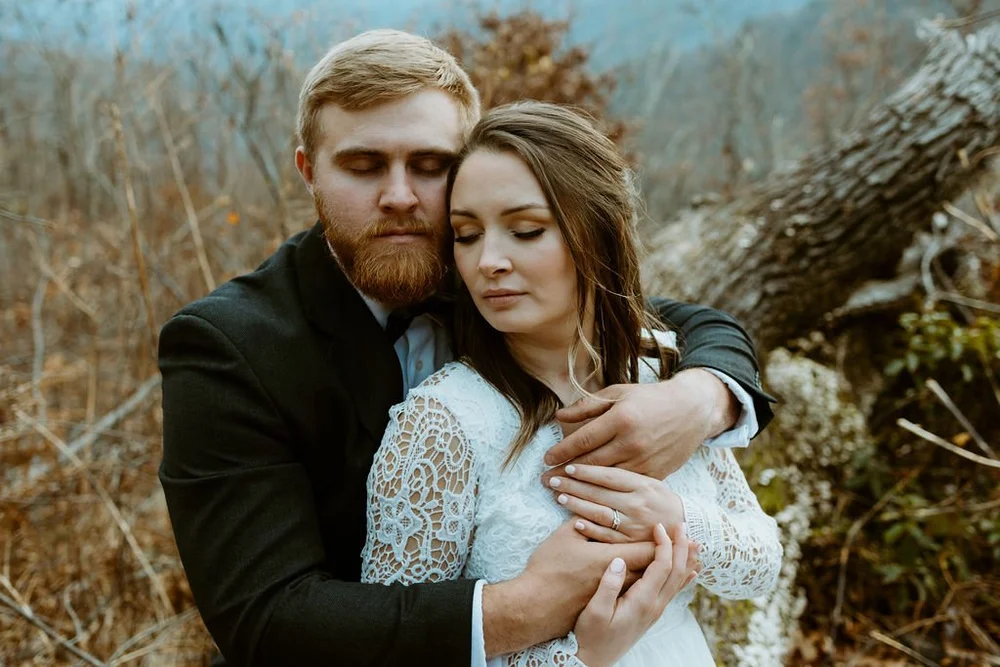 How to elope in NC? Couple places their heads lovingly together in the woods off the blue ridge parkway.