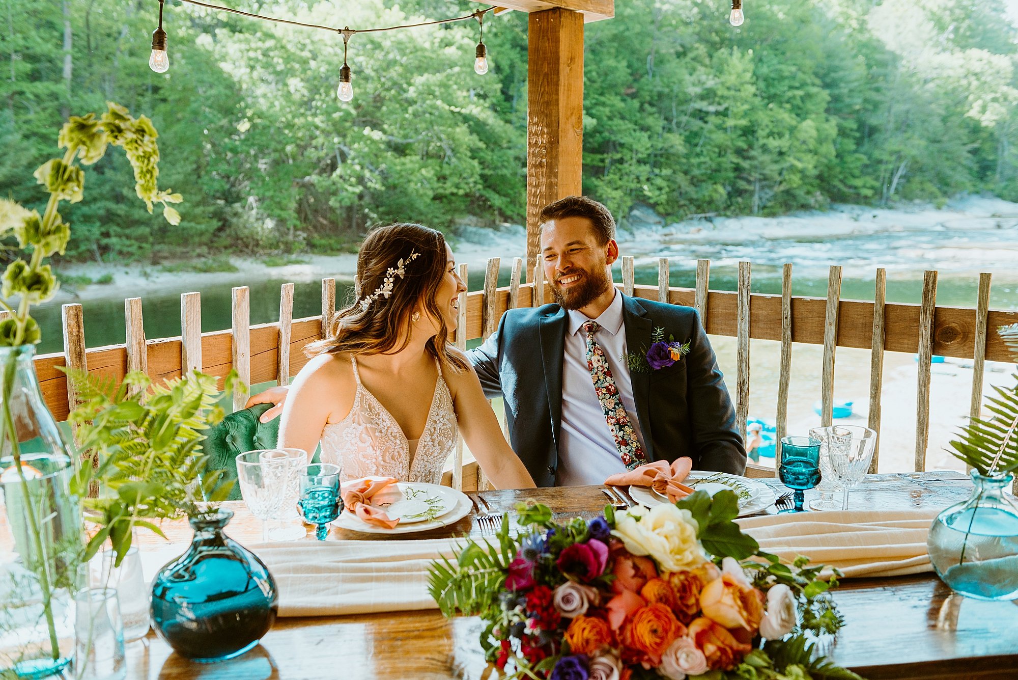 Couple hangs out at their reception table overlooking the river at Black Mountain Beach Resort