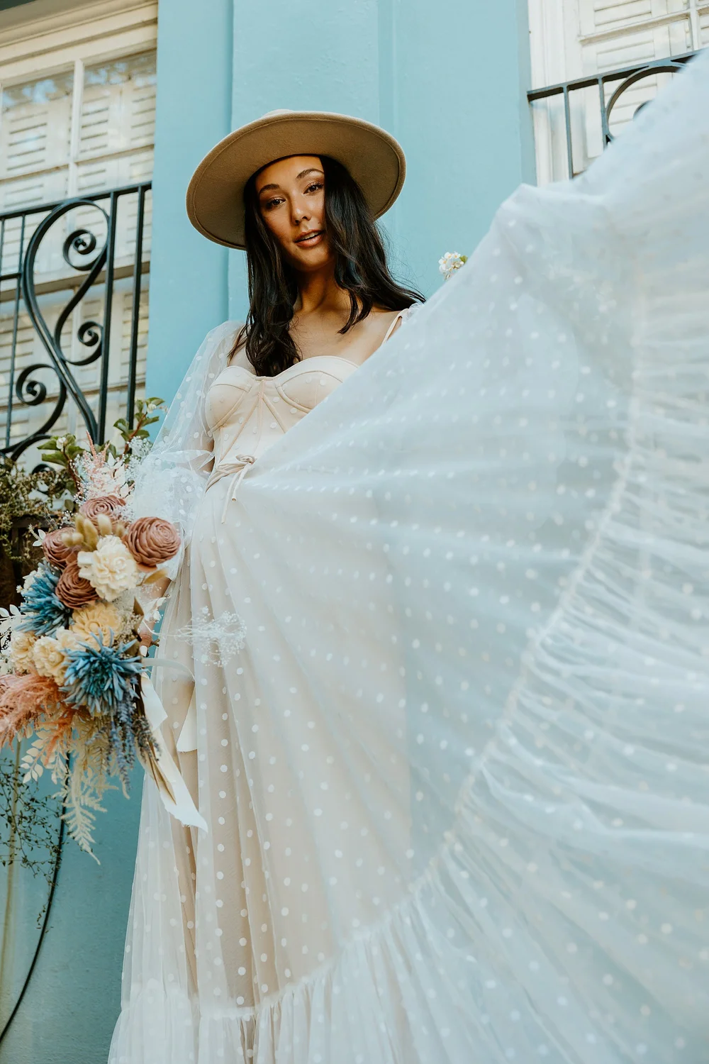 Bride stands in front of a pink house and blue house on Rainbow Row 