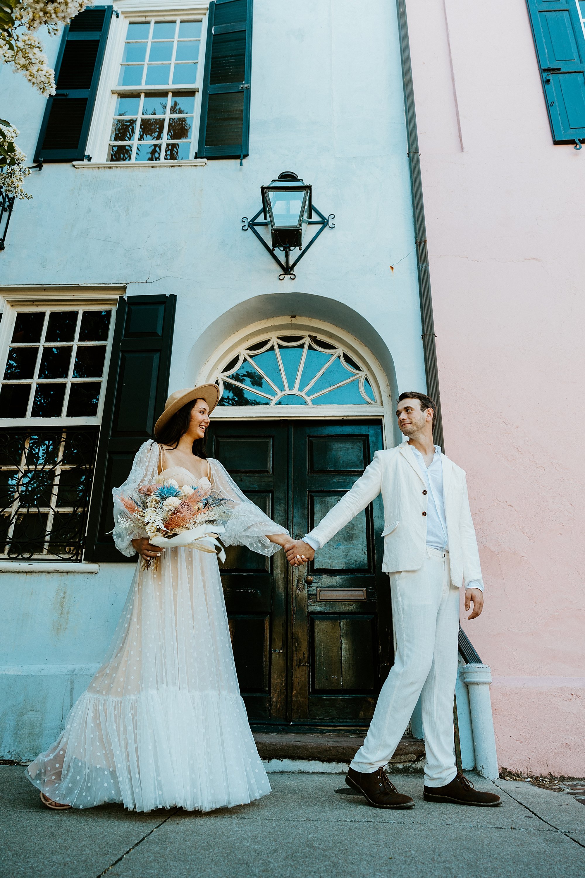 Couple walks in front of a blue houses' door on Rainbow Row