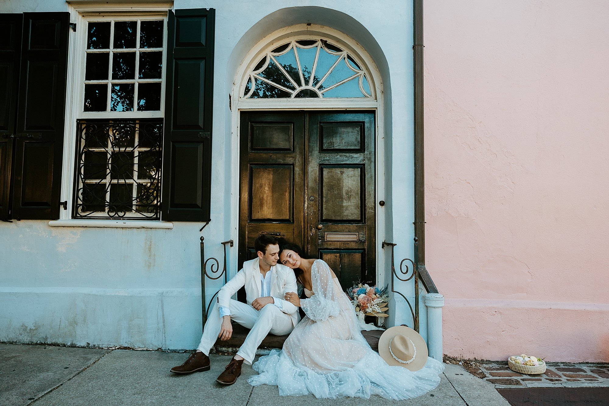 Couple sits together on a doorstep of a blue house on Rainbow Row. They are having a private moment together before they head to Folly Beach for their Charleston SC elopement.