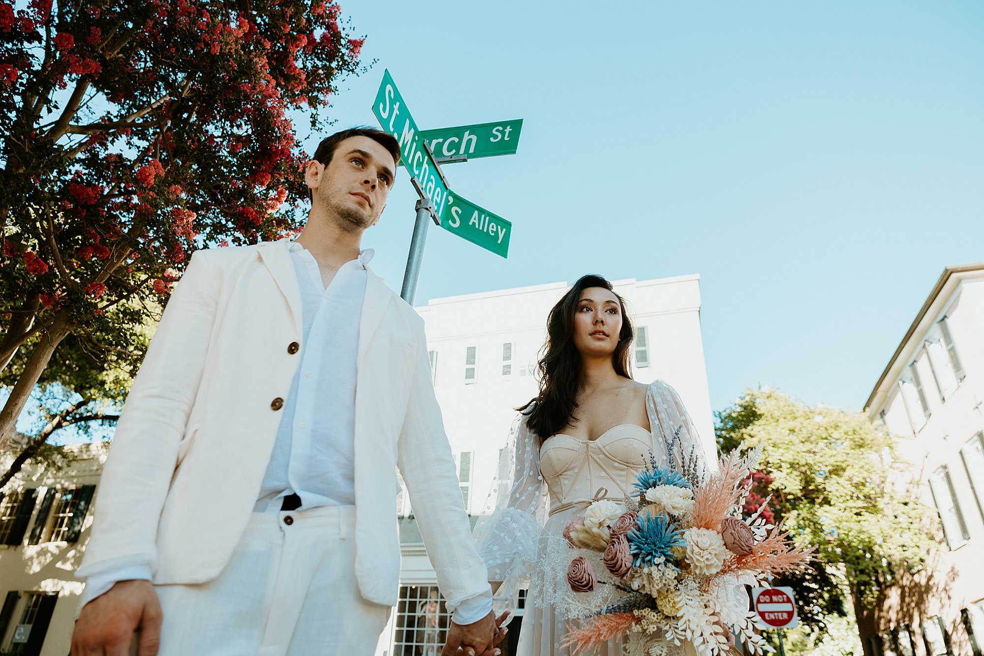 Couple stands together while waiting to cross the street in downtown Charleston SC. How to elope in Charleston SC