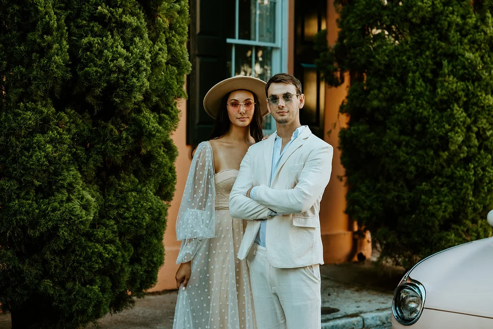 Couple poses together with their pink and blue star sunglasses on
