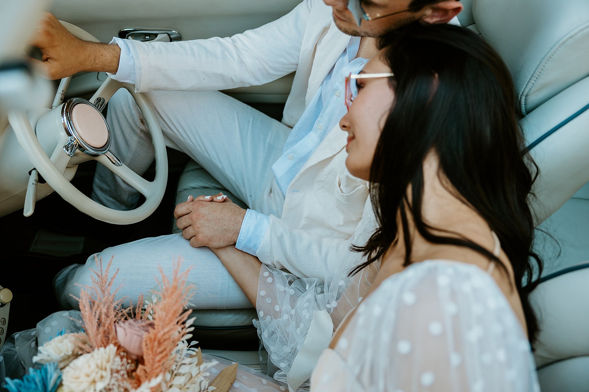 Couple sits together in The Pink Figgy car and they hold hands. How to elope in Charleston SC